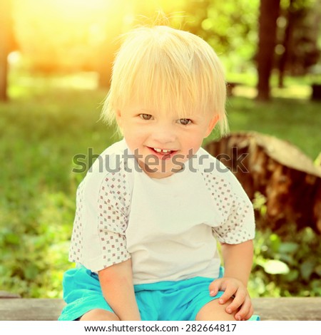 Toned Photo of the Cheerful Child on the Bench at the Summer Park