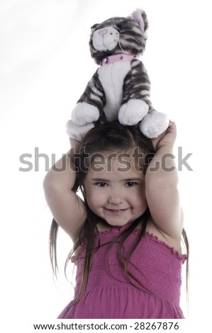 Happy five-year-old girl holding stuffed cat above her head