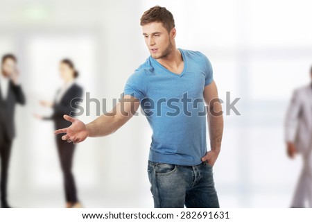 Handsome young casual man pointing down.