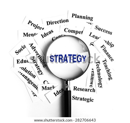 Strategy magnifying glass with some business concept word paper around it.
