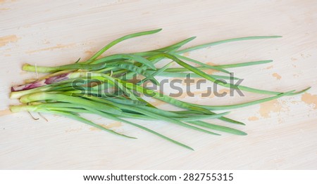 First spring green onions on a tacky white-colored wooden table