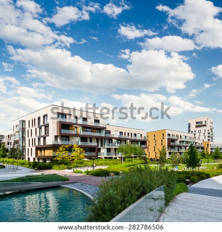 Public green park with modern blocks of flats and blue sky with white clouds Royalty-Free Stock Photo #282786506