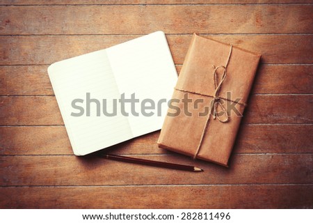 Classic notebook and pencil with parcel on wooden background. Photo in old color image style