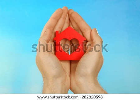 Female hands holding house on turquoise background