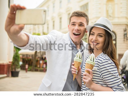 Young beautiful couple walking in the street and enjoying ice-cream. Romantic date.