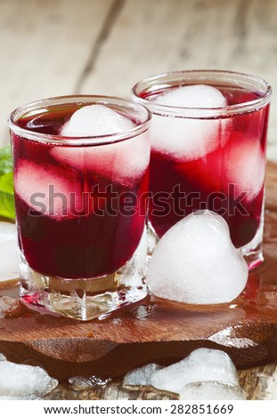 Red berry juice with ice in the shape of hearts, selective focus