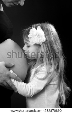 Daughter kissing pregnant mothers belly