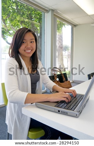 Teenage girl typing on a laptop computer in her classroom
