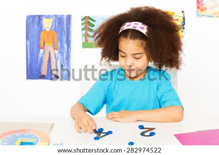 Girl puts blue coins learning to count
