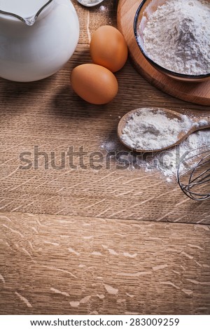flour in spoon and bowl eggs and pitcher with milk 