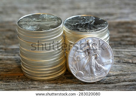 Walking liberty silver dollars stacked against weathered - aged barn wood table top