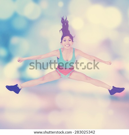 Beautiful young woman wearing sportswear doing exercise and jumping, shot against blur background