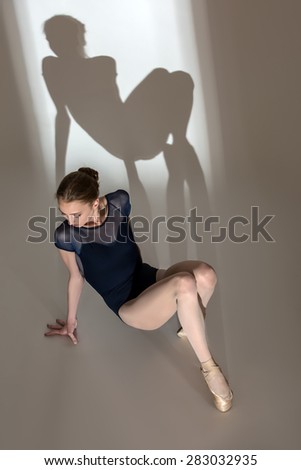 Full-length portrait sitting on the floor of a graceful ballerin