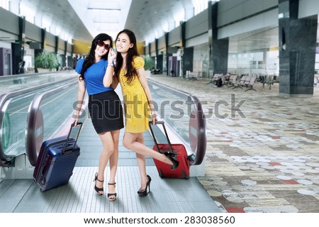 Portrait of two pretty girls traveling together and posing in the airport hall