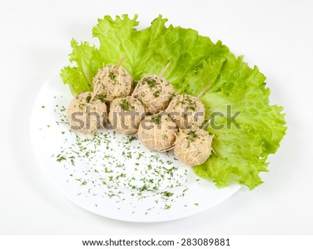 snack from chicken in the form of balls with greens on a white plate