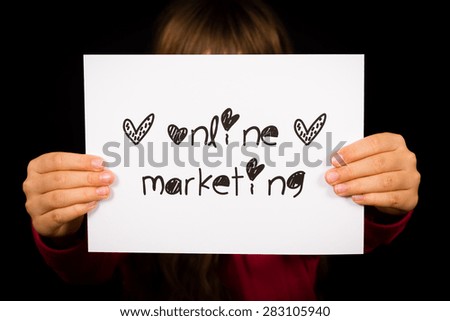 Studio shot of child holding an Online Marketing sign made of white paper with handwriting.