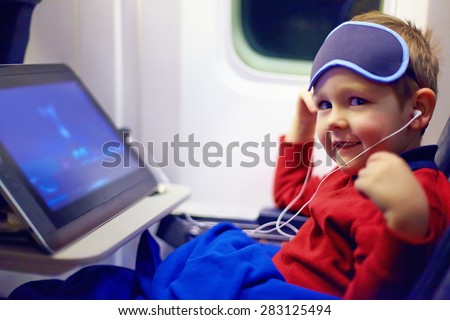 cute little kid watching cartoons during the long flight in airplane