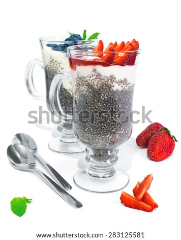 Chia jelly with fresh greek yogurt, strawberries and blueberries isolated on white 
background. Served in glasses with spoons. Selective focus.