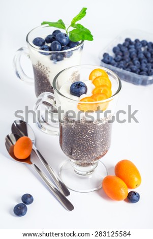 Chia jelly with greek yogurt blueberries and kumquat served in glasses with mint on white background. Selective focus.
