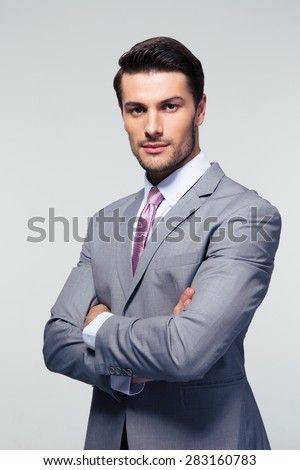 Portrait of a confident businessman with arms folded over gray background. Looking at camera