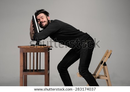 Funny and crazy man using a computer on gray background. human hands hug monitor. Concept of love to computer