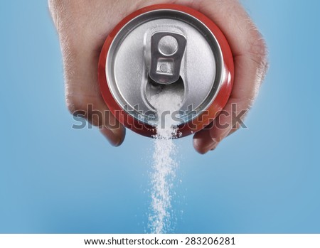 hand holding soda can pouring a crazy amount of sugar in metaphor of sugar content of a refresh drink isolated on blue background in healthy nutrition, diet and sweet addiction concept Royalty-Free Stock Photo #283206281
