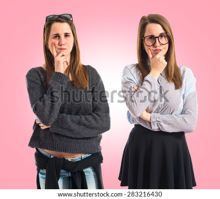 Twin sisters thinking over colorful background