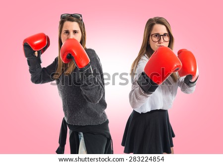 Twin sisters with boxing gloves over colorful background