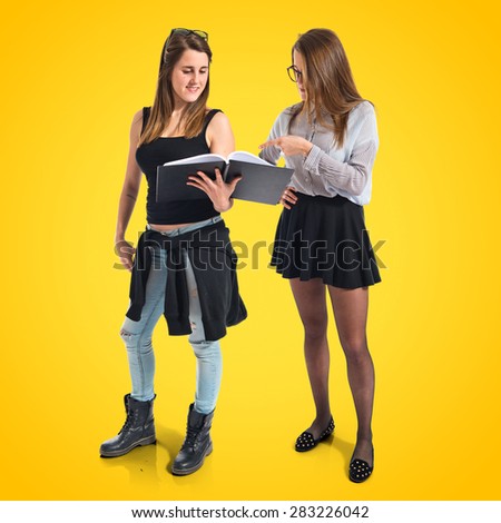 Twin sisters showing a book over colorful background