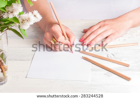 Female hands drawing on white wood background