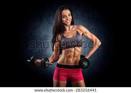 beautiful young athletic girl smiling and doing exercises with dumbbells