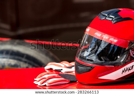 Red helmet with gloves for riding on a racing car Royalty-Free Stock Photo #283266113