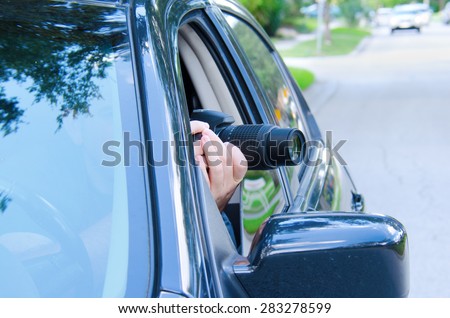Private investigator on a stakeout is photographing the situation to document the events with a camera sticking out of a car window. Royalty-Free Stock Photo #283278599