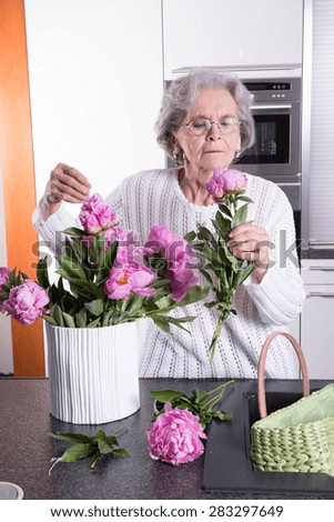 active female pensioner is smelling flowers 