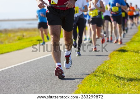 Group of runners compete in the race on coastal road Royalty-Free Stock Photo #283299872