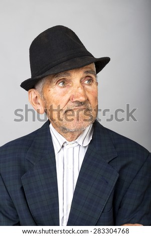 Closeup portrait of an old man with hat over gray background