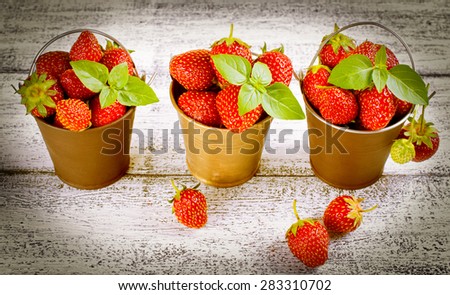 Strawberry in a small bucket on the wooden board