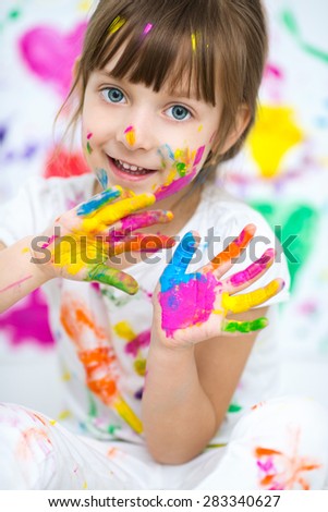 Portrait of a cute cheerful happy little girl showing her hands painted in bright color