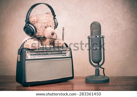 Retro radio from 60s, Teddy Bear toy with headphones and old microphone on table. Vintage instagram style filtered conceptual photo Royalty-Free Stock Photo #283361450