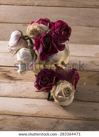 Image of withered red white roses on wood background.