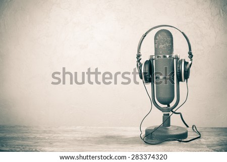 Retro studio ribbon microphone from 50s with headphones on table. Vintage old style sepia photo Royalty-Free Stock Photo #283374320
