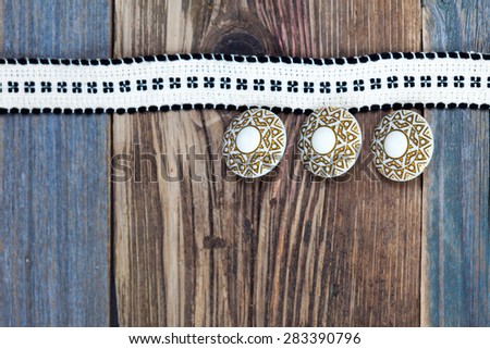 Vintage tape with embroidered pattern and three ancient buttons on the old textured boards