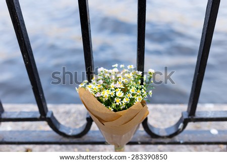 Bouquet on craft paper decoration with daisies in metal construction over stone and water background. Close up