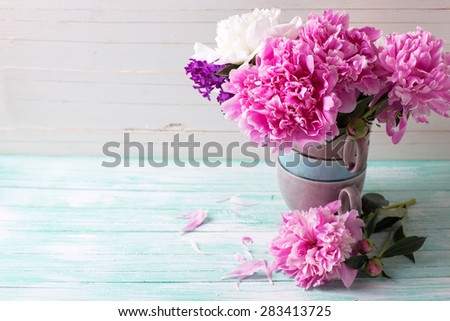 Splendid  pink  peonies flowers in vase  on turquoise painted wooden planks against white wall. Selective focus. Place for text.