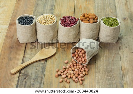 Different kinds of beans in sacks bag, focus on scattered peanut