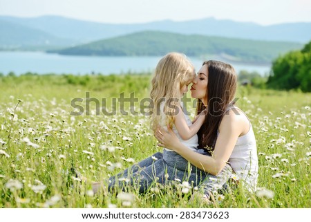 mother hugging with toddler girl in daisy field