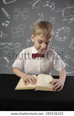 little pupil sitting at the desk and reading a book