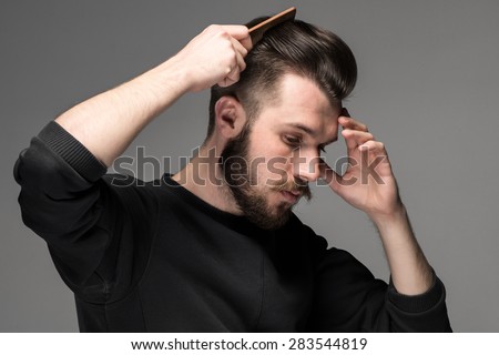 young man comb his hair on gray background Royalty-Free Stock Photo #283544819