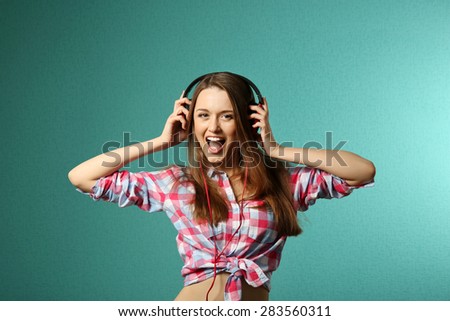 Young woman with headphones on turquoise background