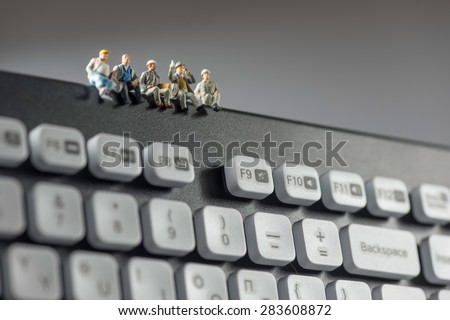 Miniature workers sitting on top of keyboard. Technology concept. Macro photo Royalty-Free Stock Photo #283608872